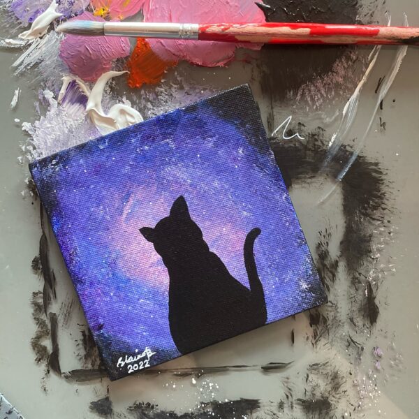 Silhouette of a cat against purple galaxy light.