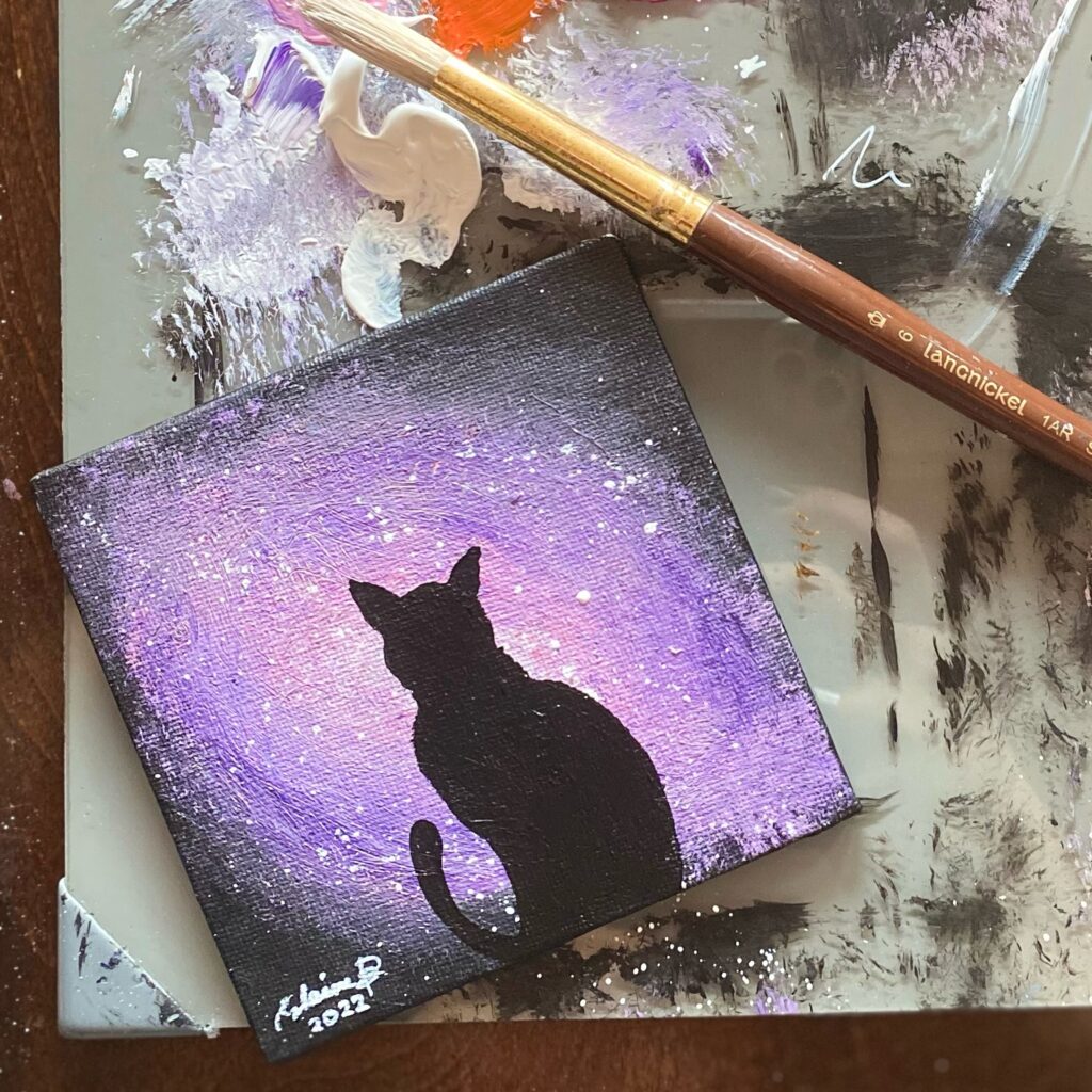 Silhouette of a cat against pink galaxy light.