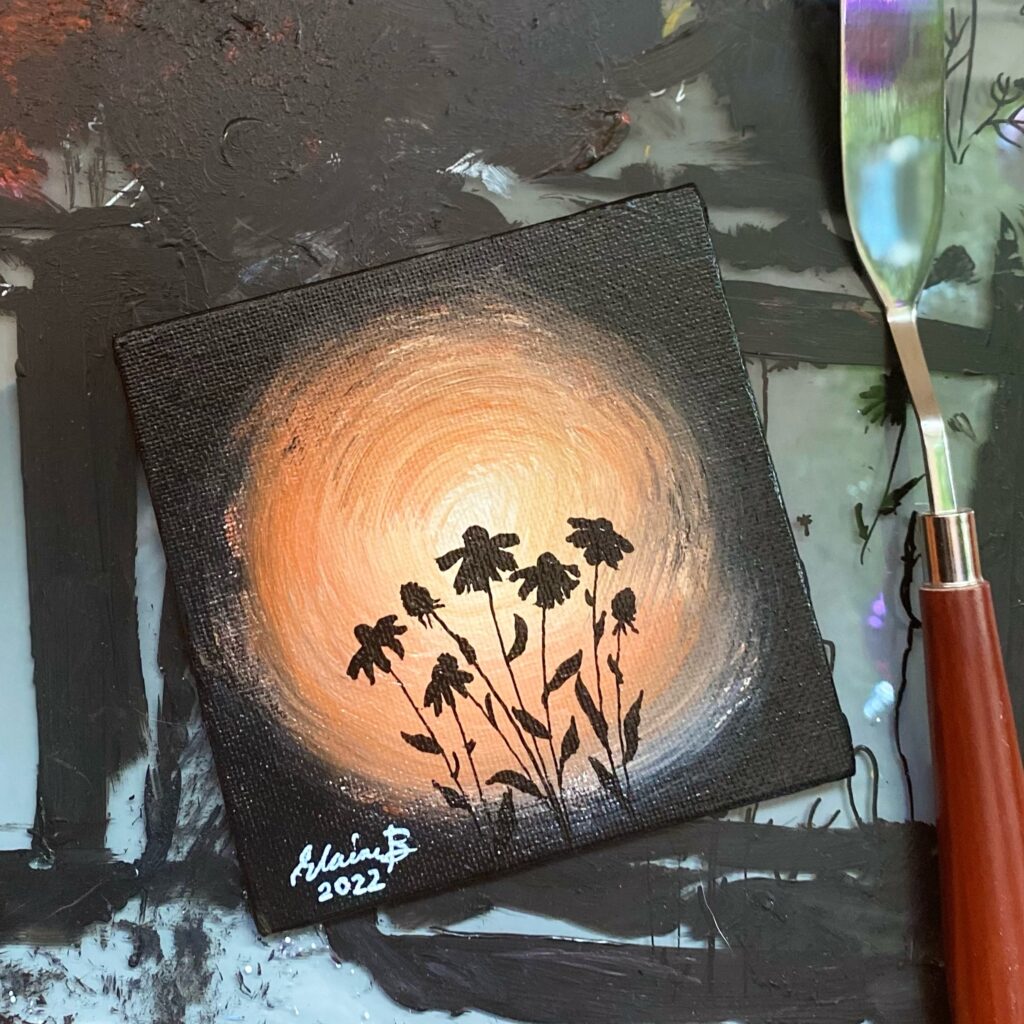 Silhouette of chamomile flowers against orange light.