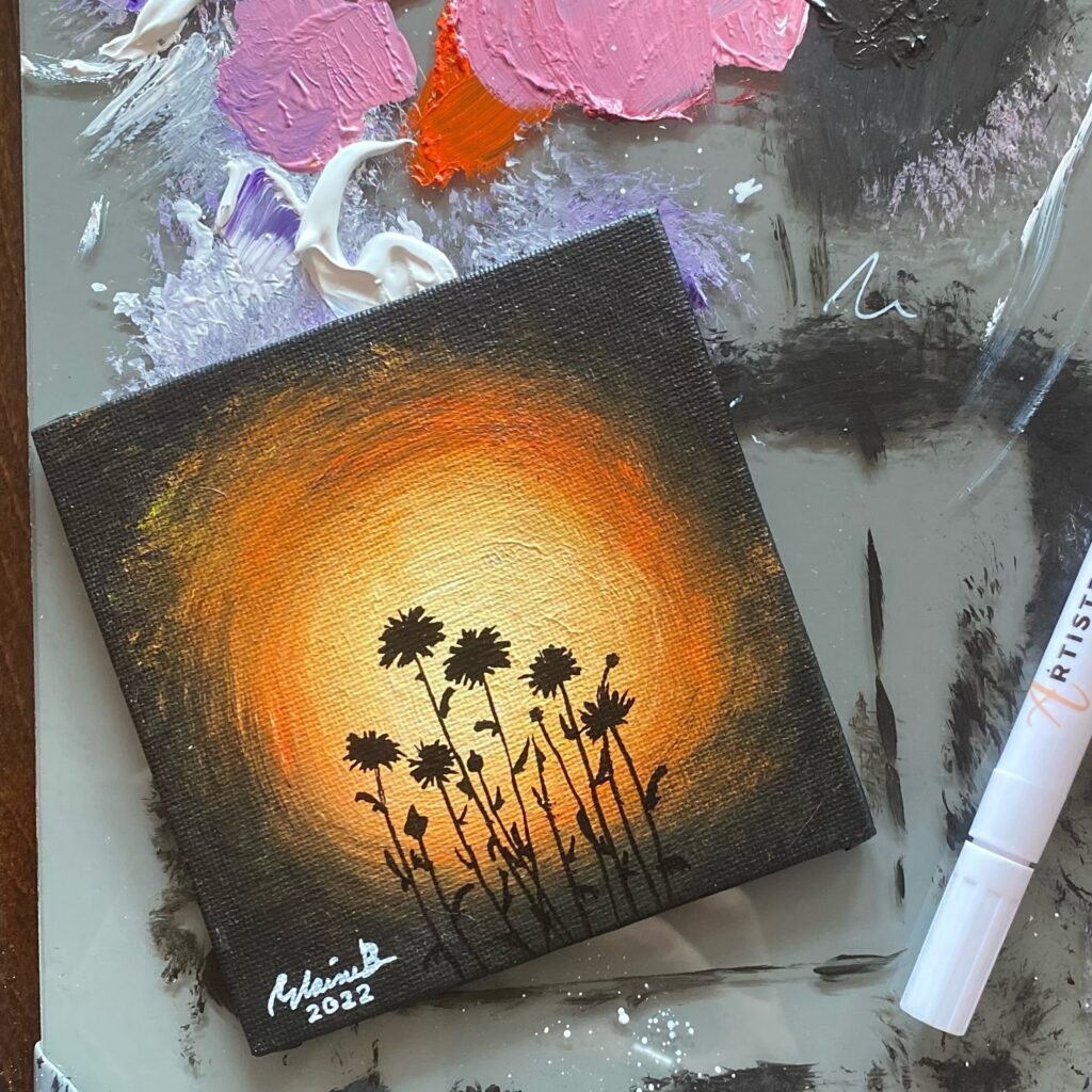 Silhouette of dandelions against orange light.