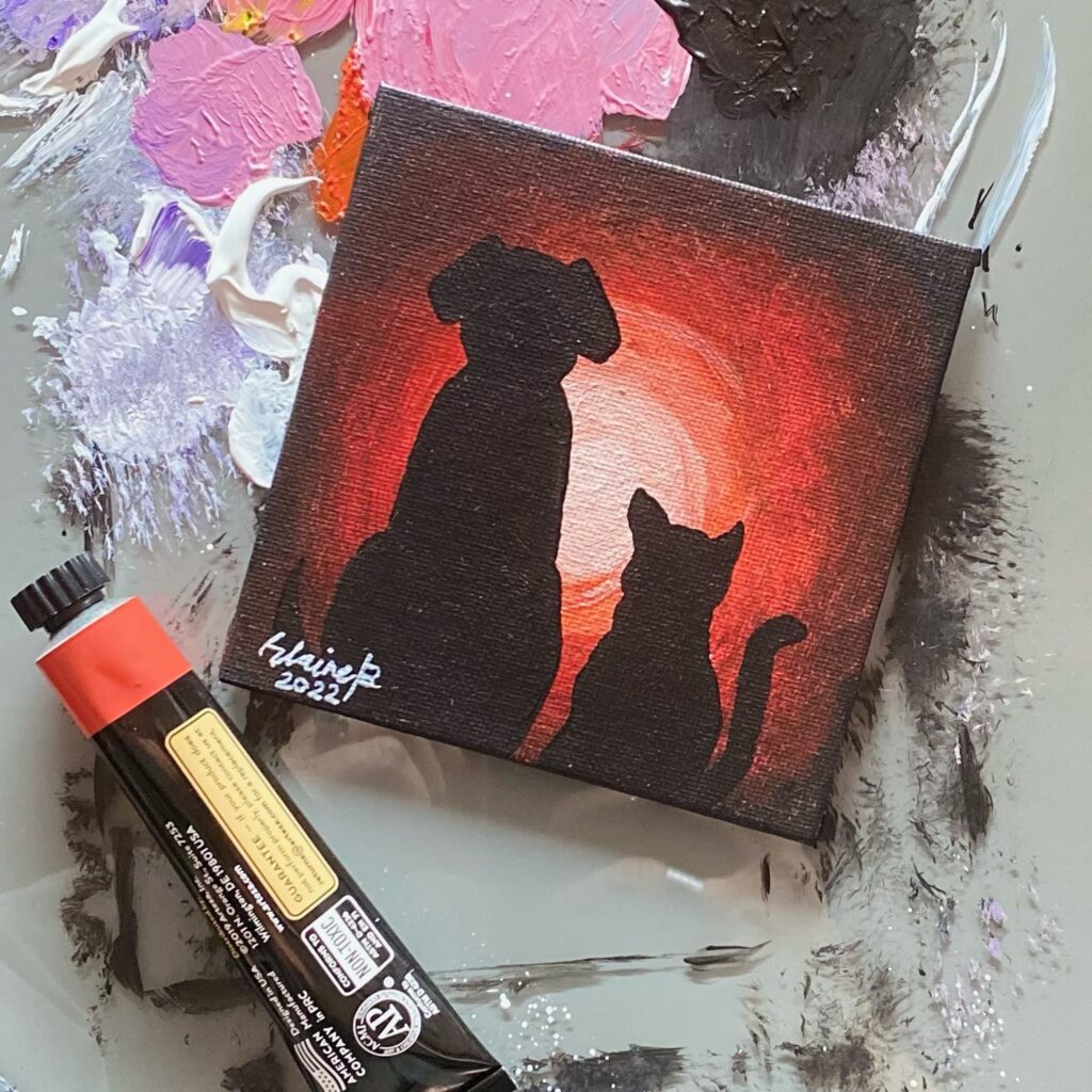 Silhouette of a dog and a cat against red galaxy light.