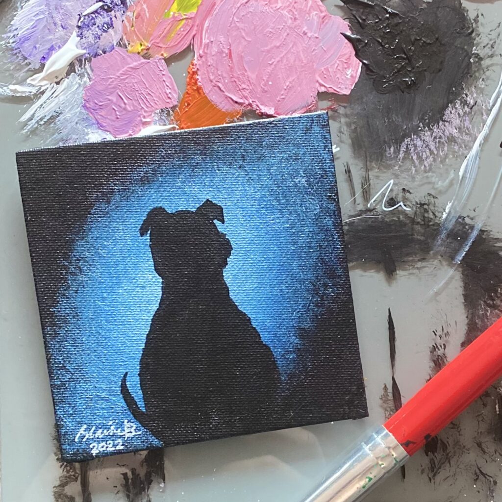 Silhouette of a pitbull against blue galaxy light.